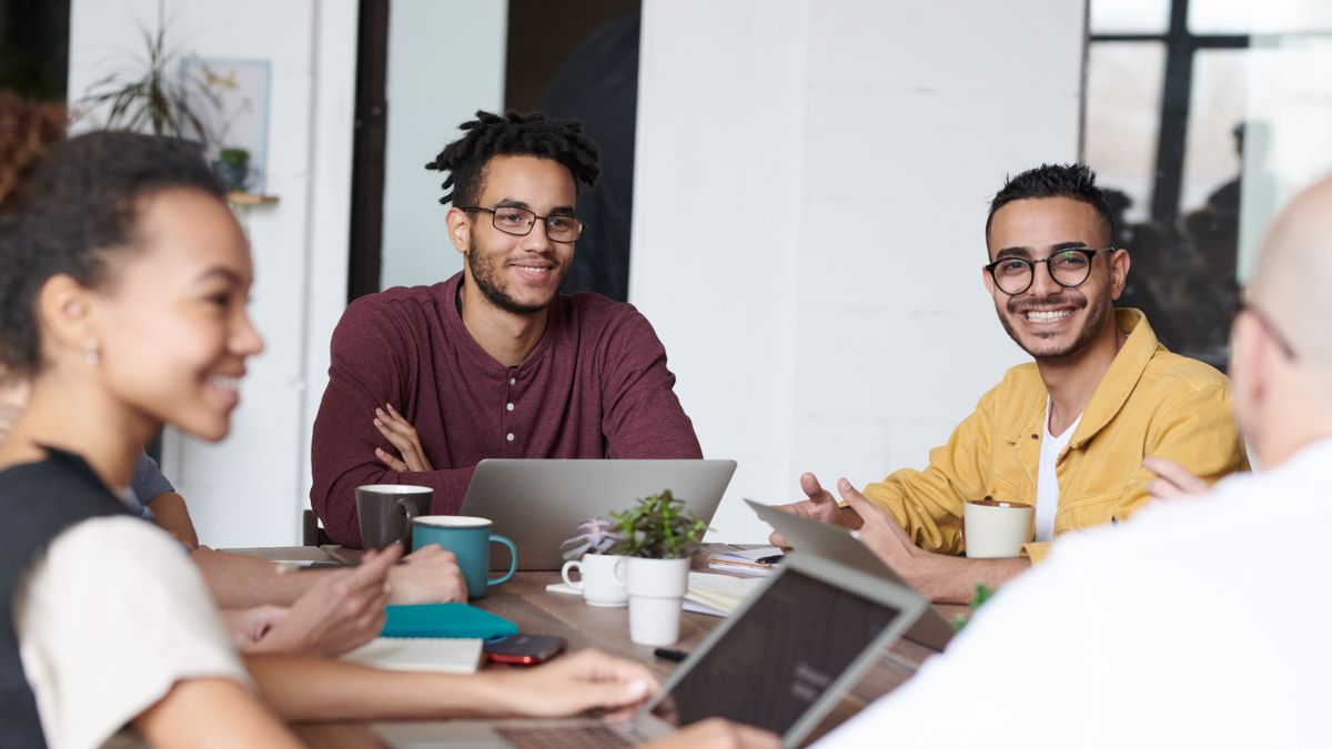 Diverse group of coworkers laughing together around a table during a team social
