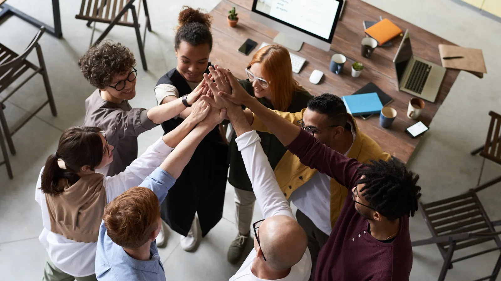 Small team of colleagues joining hands together in a circle during a team activity